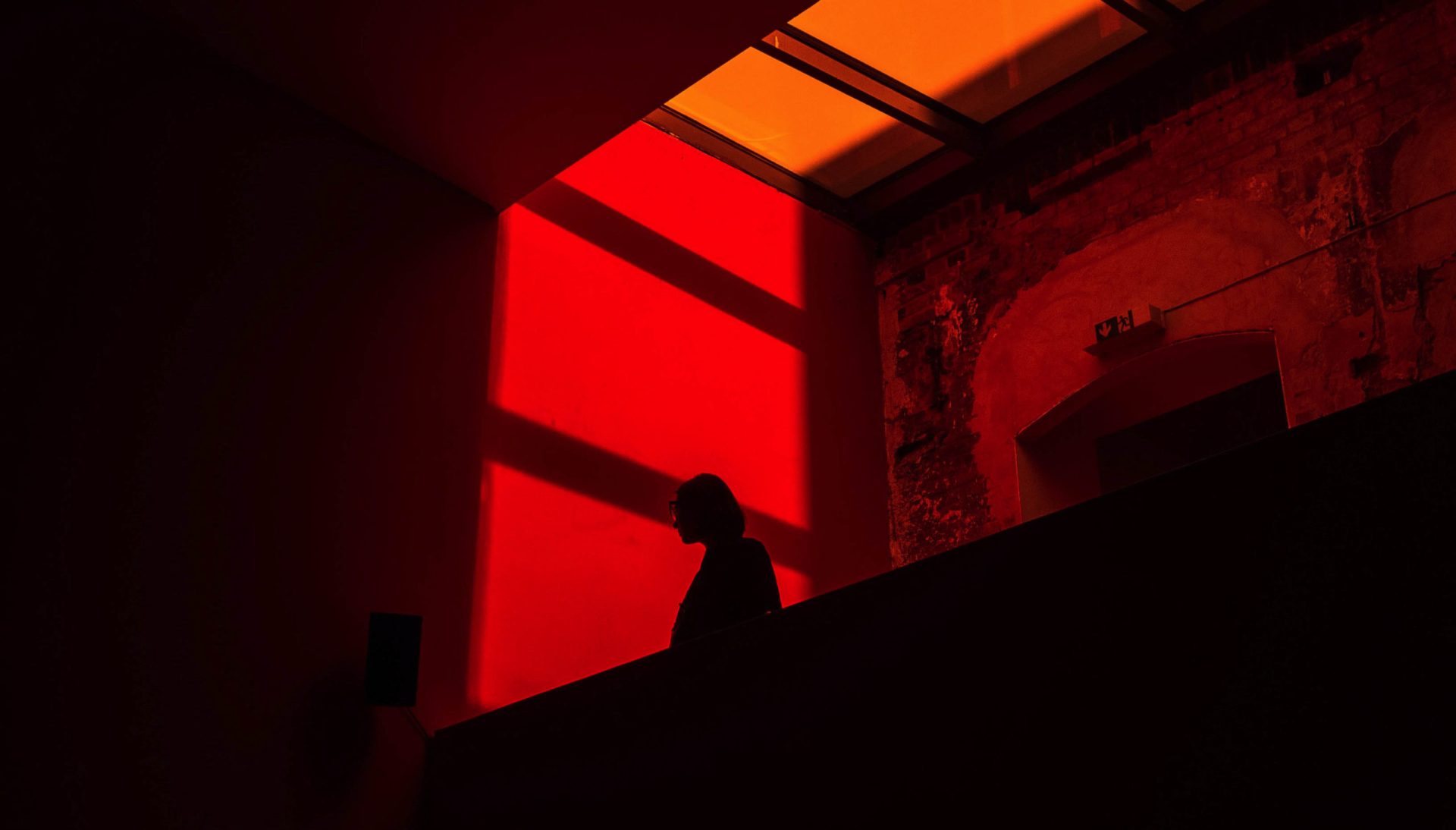 A person standing in an elevated place with orange light filling up the space