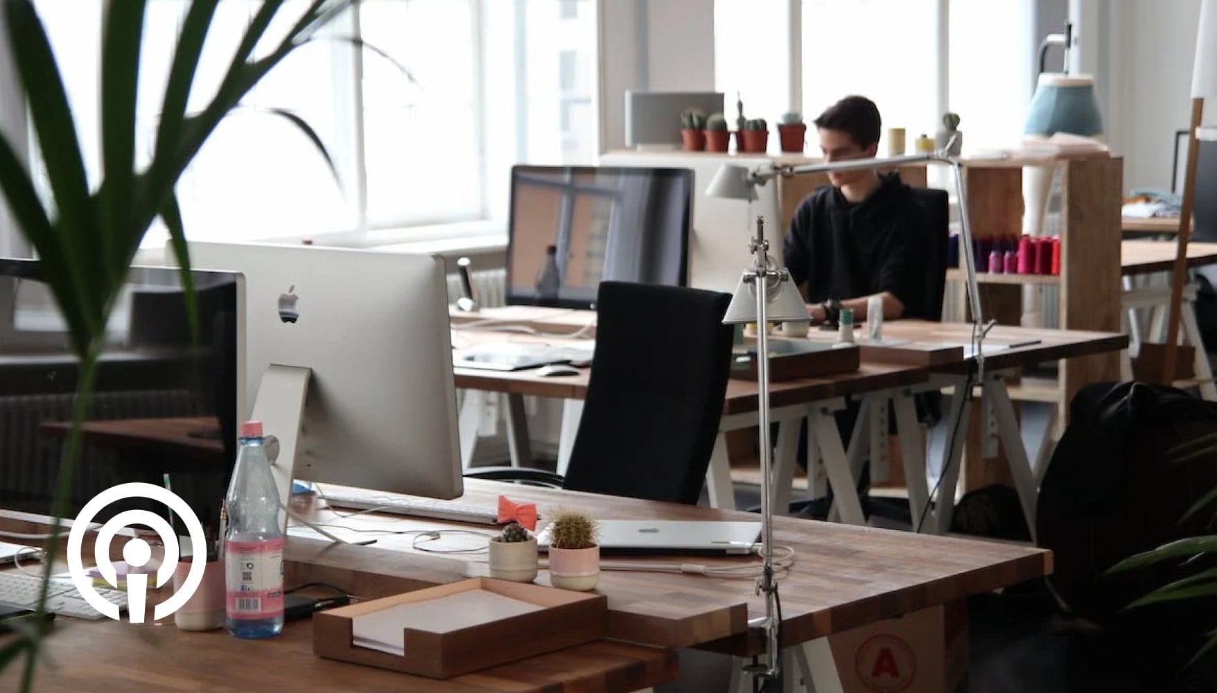 A designer seen from a distance working on his computer desk