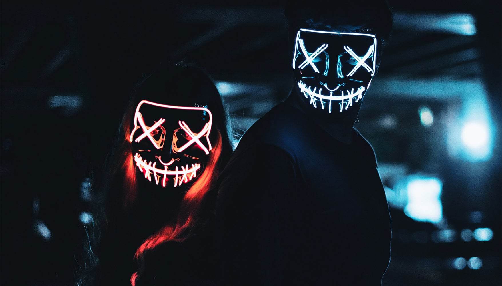 A photo of two people wearing LED masks depicting toxicity.